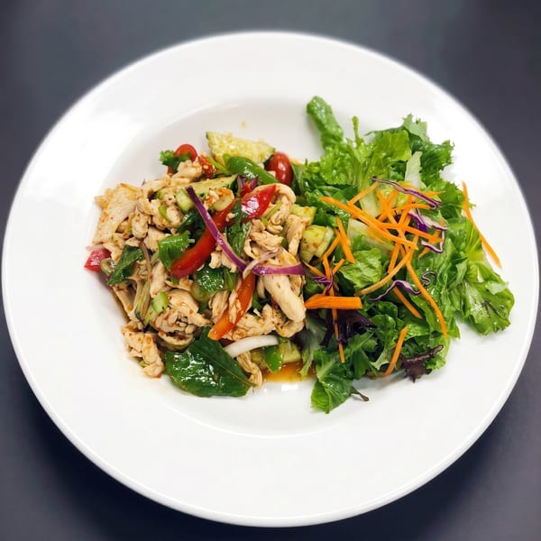 Spicy chicken salad with red peppers, onions, and a side of mixed greens.