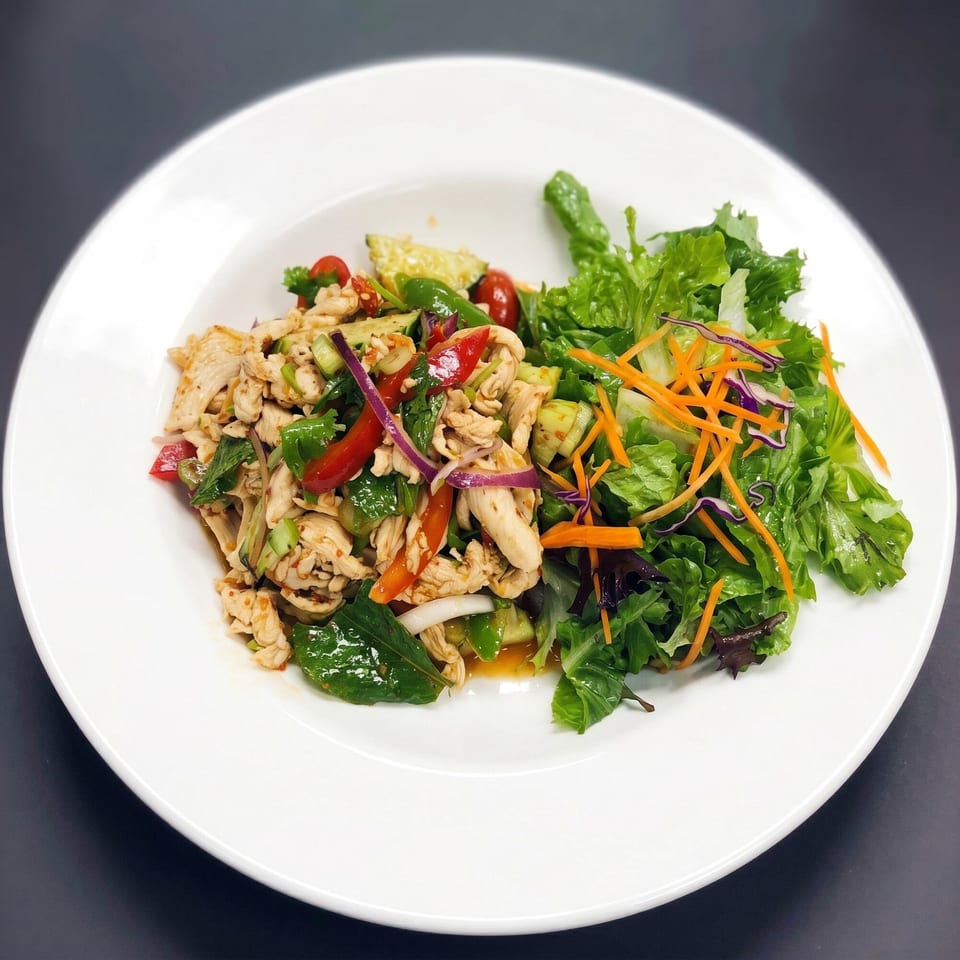 Spicy chicken salad with red peppers, onions, and a side of mixed greens.
